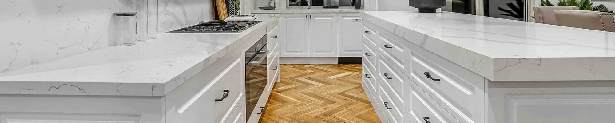 Herringbone hardwood floor in a kitchen with white cabinets